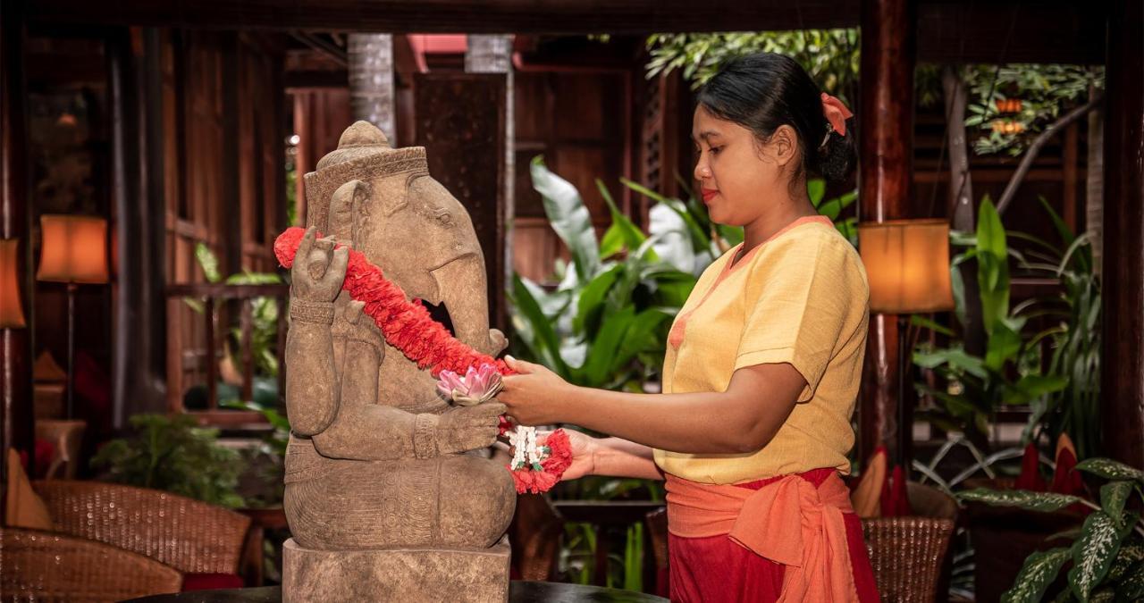 Angkor Village Hotel - Small Luxury Hotels Of The World Siem Reap Zewnętrze zdjęcie A woman in Thailand, wearing traditional Thai clothing, garlands a statue of the Hindu god Ganesha.